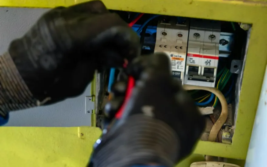 Manos con guantes midiendo dentro de un tablero con la punta de prueba