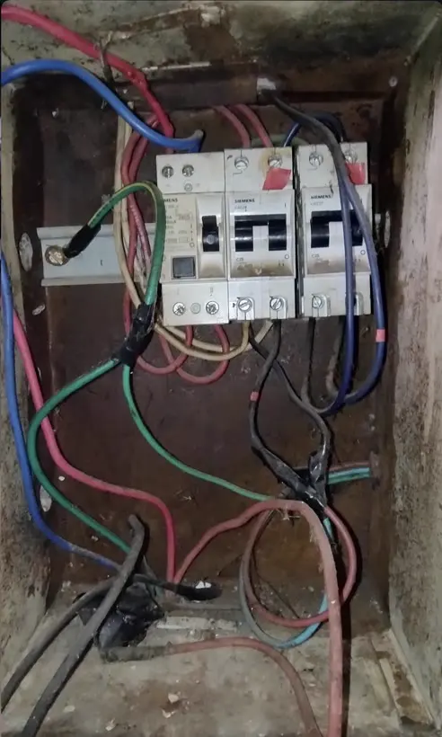 Gabinete oxidado con protecciones viejas y cables sueltos